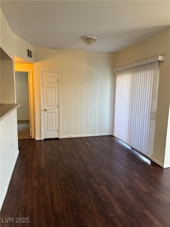 unfurnished room with baseboards, visible vents, and wood finished floors