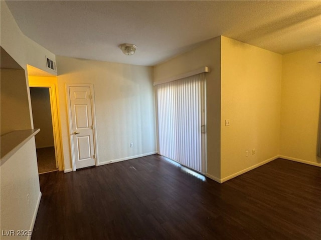 spare room featuring baseboards, a textured ceiling, wood finished floors, and visible vents