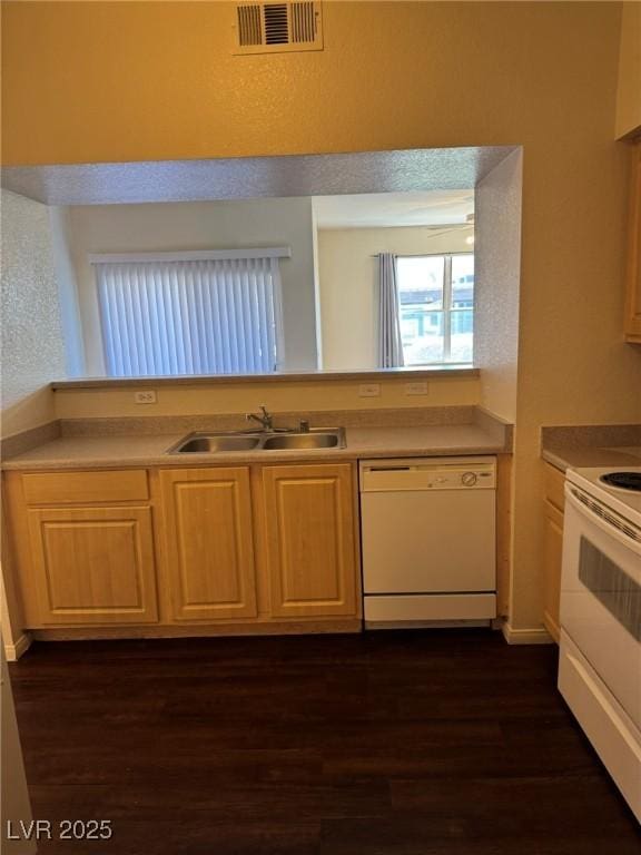 kitchen with a sink, white appliances, light countertops, visible vents, and dark wood-style floors