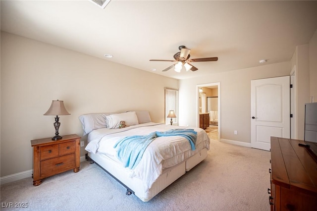 bedroom with baseboards, light carpet, a ceiling fan, and ensuite bath