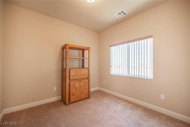 spare room with visible vents, baseboards, and light carpet