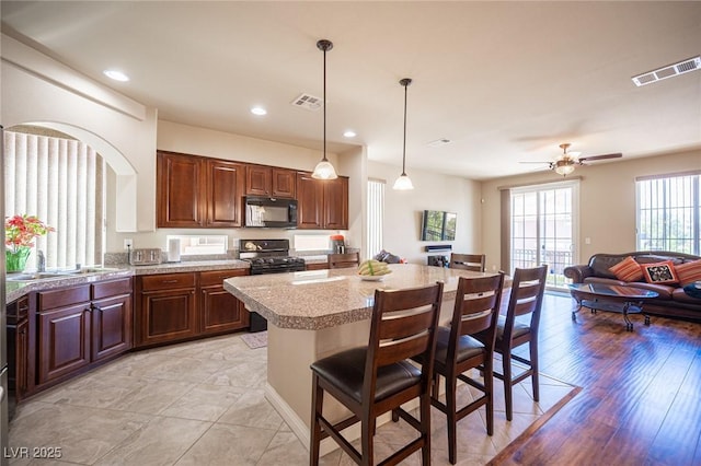 kitchen featuring a kitchen breakfast bar, visible vents, a sink, and black appliances