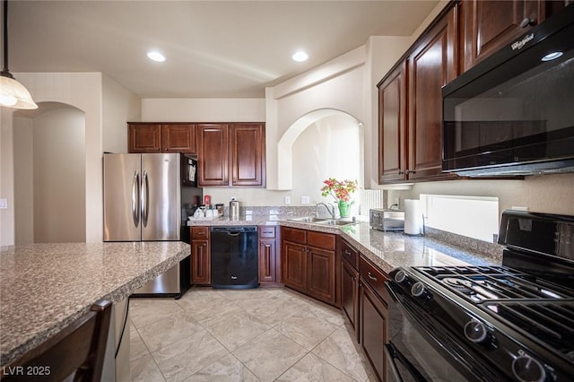kitchen with arched walkways, a sink, black appliances, and decorative light fixtures