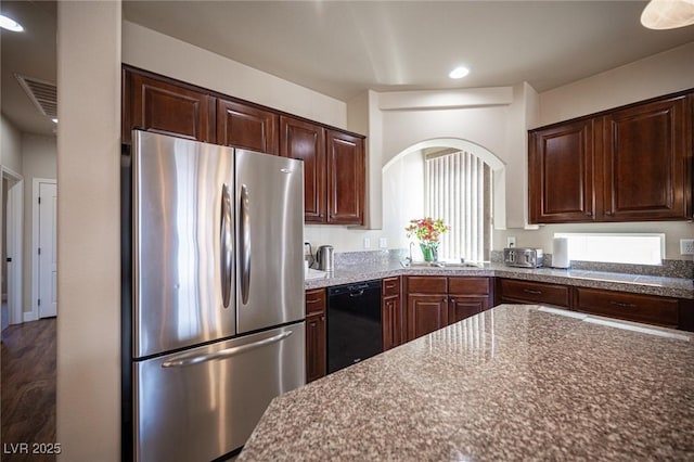 kitchen with arched walkways, dark brown cabinets, freestanding refrigerator, black dishwasher, and recessed lighting