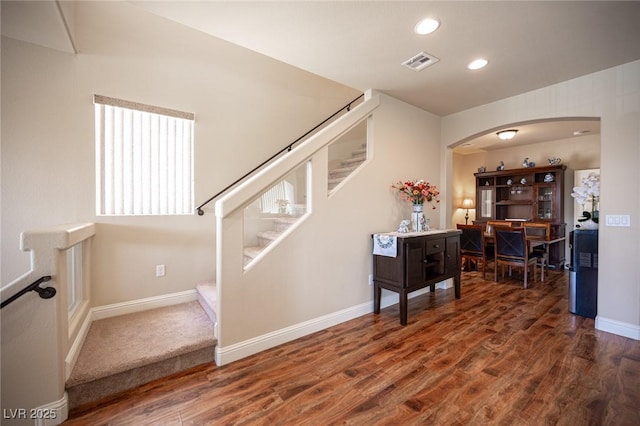 stairway with arched walkways, recessed lighting, baseboards, wood finished floors, and visible vents