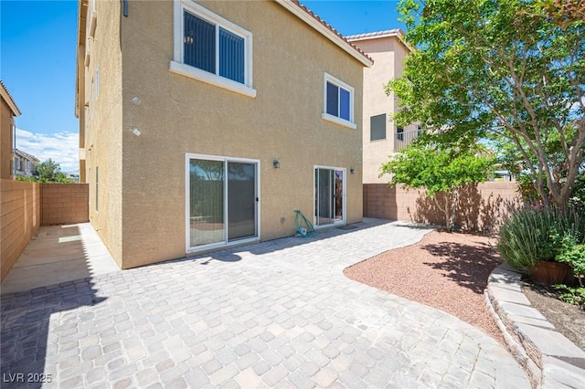 back of property featuring a fenced backyard, a patio, and stucco siding
