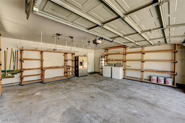 garage featuring stainless steel refrigerator with ice dispenser, washer and clothes dryer, and a garage door opener