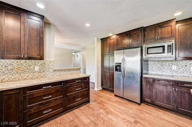kitchen featuring light wood-style floors, backsplash, stainless steel appliances, and dark brown cabinetry
