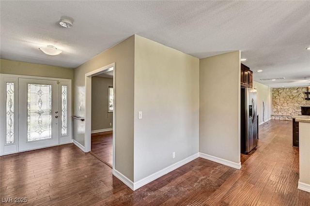 foyer entrance with baseboards, a textured ceiling, and dark wood-style flooring