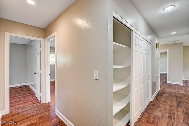 corridor with baseboards, recessed lighting, and wood finished floors