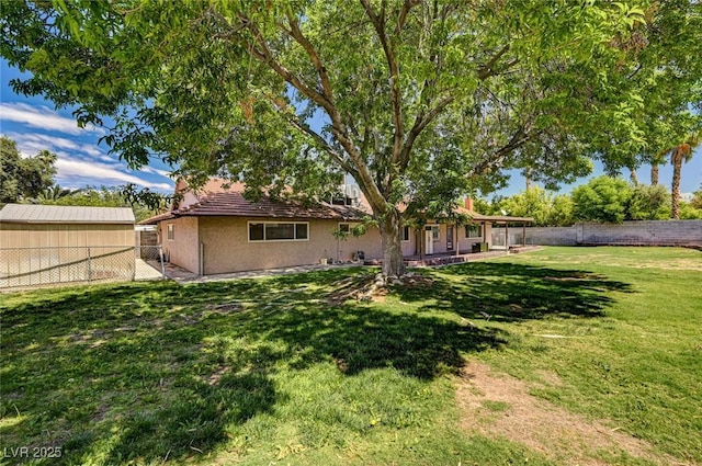 back of house with a lawn, a fenced backyard, and stucco siding