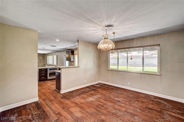 kitchen with a notable chandelier, baseboards, stainless steel oven, and dark wood finished floors