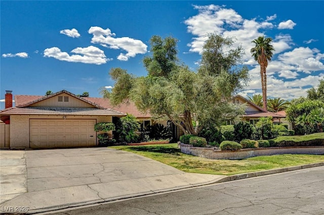 view of front of property featuring an attached garage, a tiled roof, a front yard, and concrete driveway