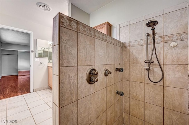 full bath with visible vents, vanity, tile patterned floors, and tiled shower