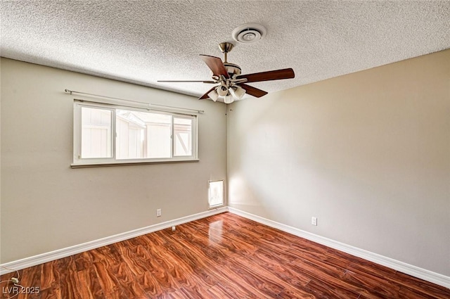 spare room featuring visible vents, wood finished floors, baseboards, ceiling fan, and a textured ceiling