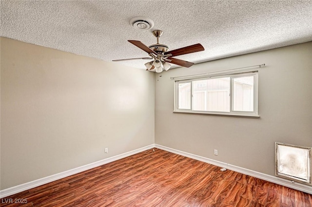 empty room featuring visible vents, wood finished floors, baseboards, a textured ceiling, and a ceiling fan