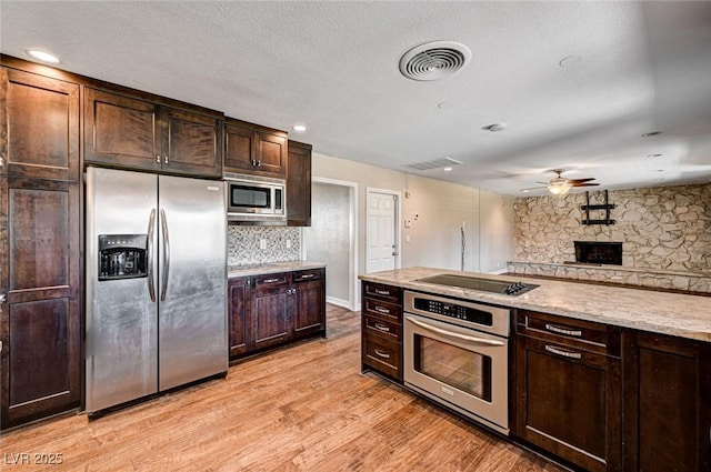 kitchen featuring visible vents, tasteful backsplash, a ceiling fan, light wood-style flooring, and stainless steel appliances