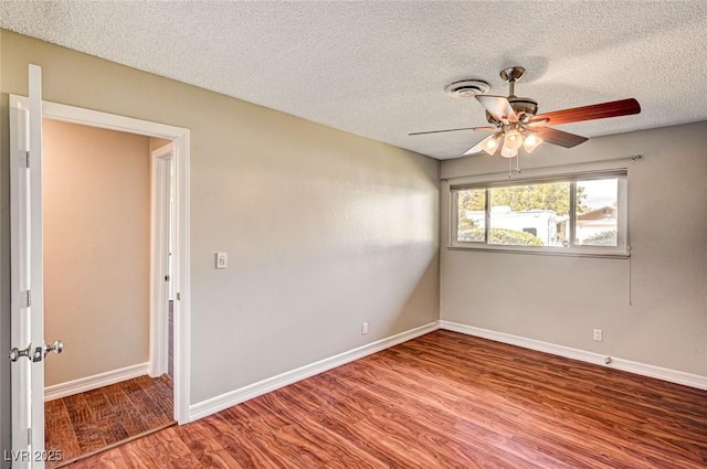 spare room with baseboards, ceiling fan, a textured ceiling, and wood finished floors