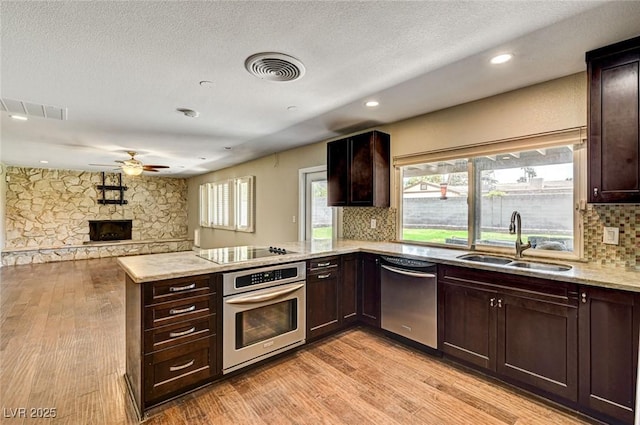 kitchen with a sink, light wood-style flooring, ceiling fan, and stainless steel appliances