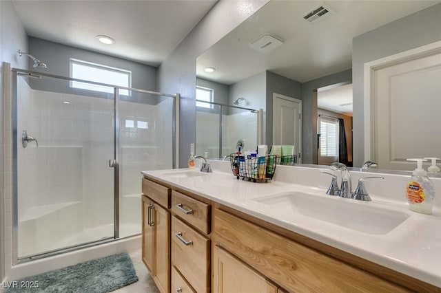 bathroom with double vanity, visible vents, a sink, and a stall shower