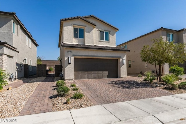 traditional-style home featuring a gate, stucco siding, an attached garage, and decorative driveway