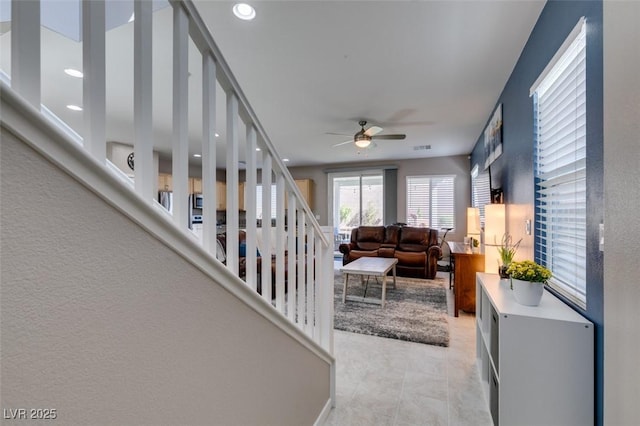 living area featuring a ceiling fan and stairs