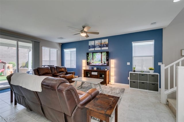 living room featuring ceiling fan, stairs, light tile patterned flooring, and visible vents