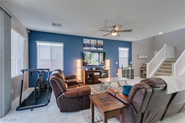 living room featuring light tile patterned floors, a ceiling fan, stairs, and visible vents