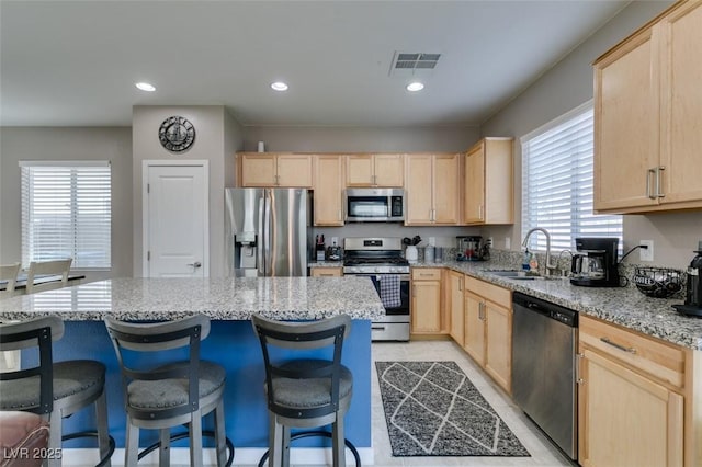 kitchen featuring light brown cabinetry, appliances with stainless steel finishes, plenty of natural light, and a sink