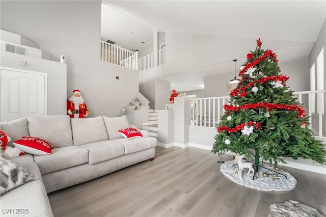 living room with high vaulted ceiling, baseboards, wood finished floors, and visible vents