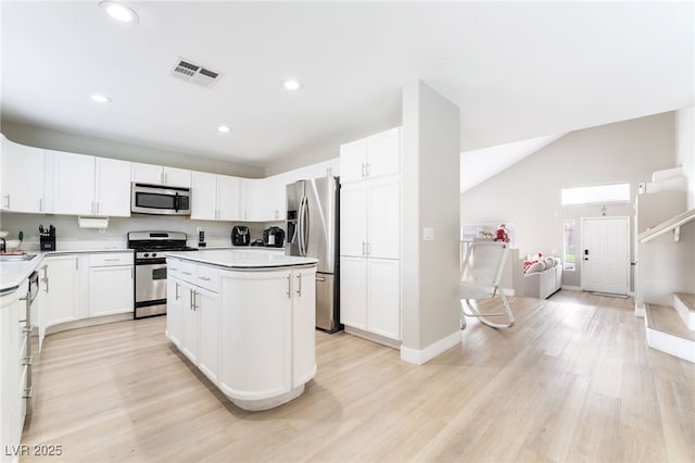 kitchen featuring appliances with stainless steel finishes, a center island, light wood finished floors, and visible vents
