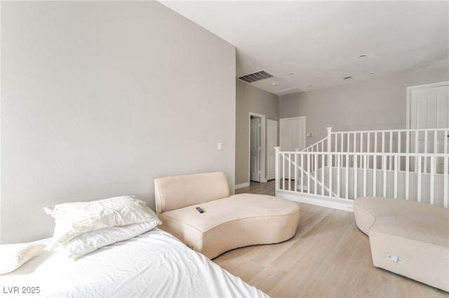 bedroom with baseboards, visible vents, and wood finished floors