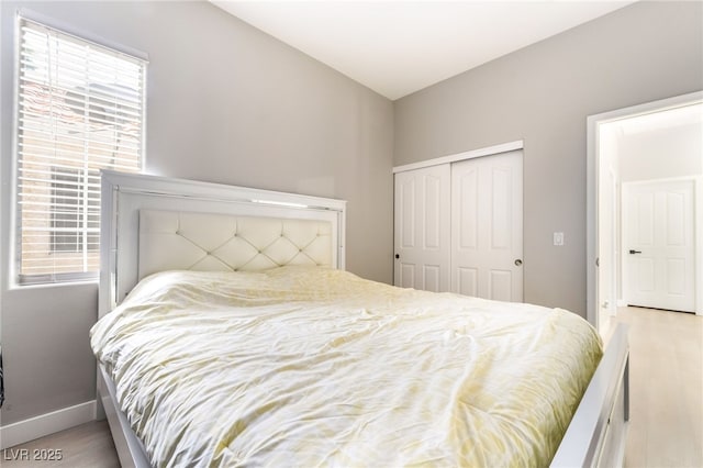 bedroom featuring baseboards, multiple windows, a closet, and wood finished floors