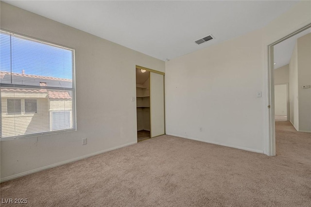 unfurnished bedroom featuring baseboards, light carpet, a closet, and visible vents