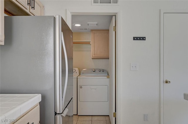 washroom featuring cabinet space, visible vents, washing machine and dryer, and light tile patterned floors
