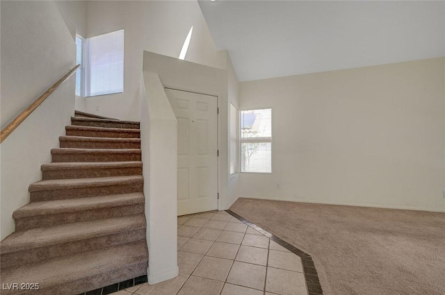 stairway featuring vaulted ceiling, tile patterned flooring, and carpet flooring