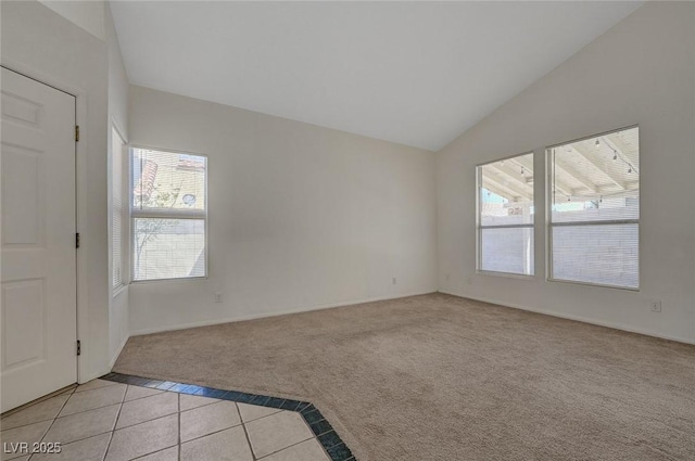 spare room featuring light tile patterned floors, baseboards, light carpet, and lofted ceiling