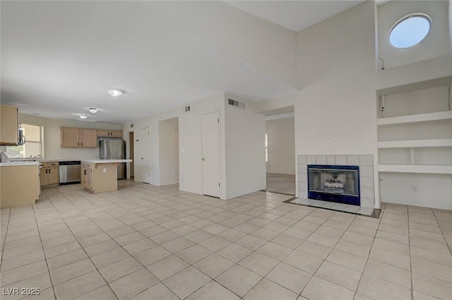 unfurnished living room with light tile patterned floors, a fireplace, built in shelves, and visible vents