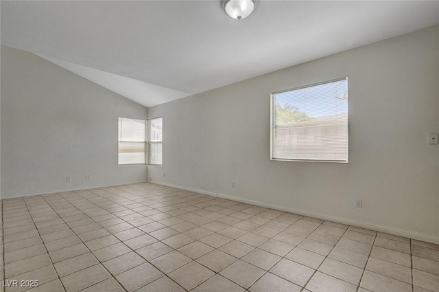 empty room with baseboards, light tile patterned floors, and vaulted ceiling