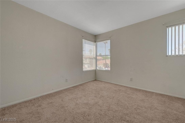 spare room with baseboards and light colored carpet