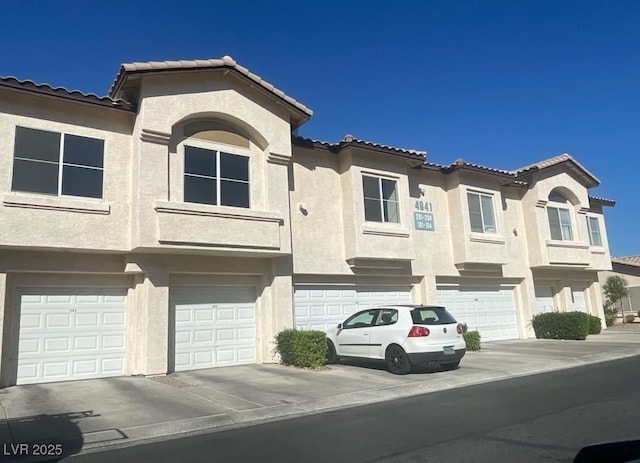 4941 Black Bear Rd Unit 202, Las Vegas, NV 89149 - view of front of house with an attached garage, driveway, a tile roof, and stucco siding