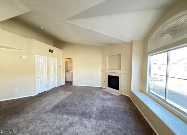 4941 Black Bear Rd Unit 202, Las Vegas, NV 89149 - unfurnished living room featuring visible vents, carpet floors, a tiled fireplace, arched walkways, and vaulted ceiling
