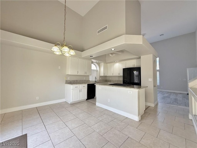kitchen with visible vents, black appliances, white cabinets, a sink, and a notable chandelier