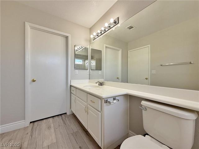 bathroom featuring vanity, wood finished floors, and toilet
