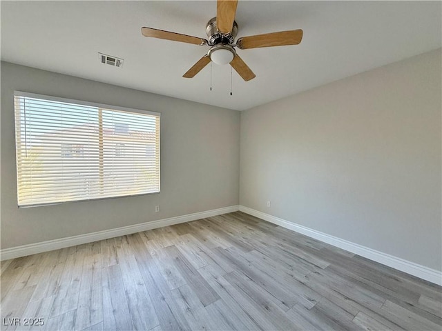 spare room featuring a ceiling fan, baseboards, visible vents, and wood finished floors