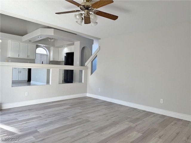 unfurnished living room with baseboards, a ceiling fan, and light wood-style flooring