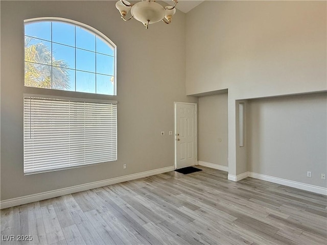 entryway featuring wood finished floors, a high ceiling, and a chandelier