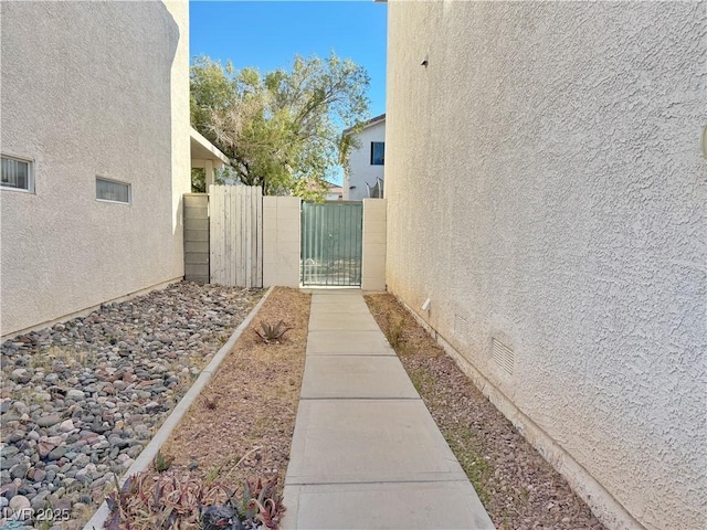 view of property exterior featuring crawl space, fence, a gate, and stucco siding