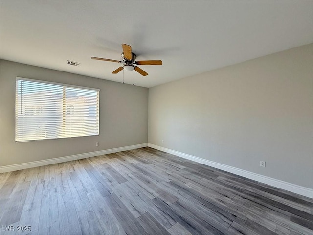 unfurnished room featuring a ceiling fan, baseboards, visible vents, and wood finished floors