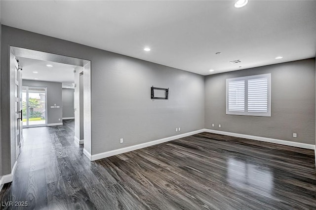 empty room featuring recessed lighting, baseboards, dark wood-style flooring, and visible vents
